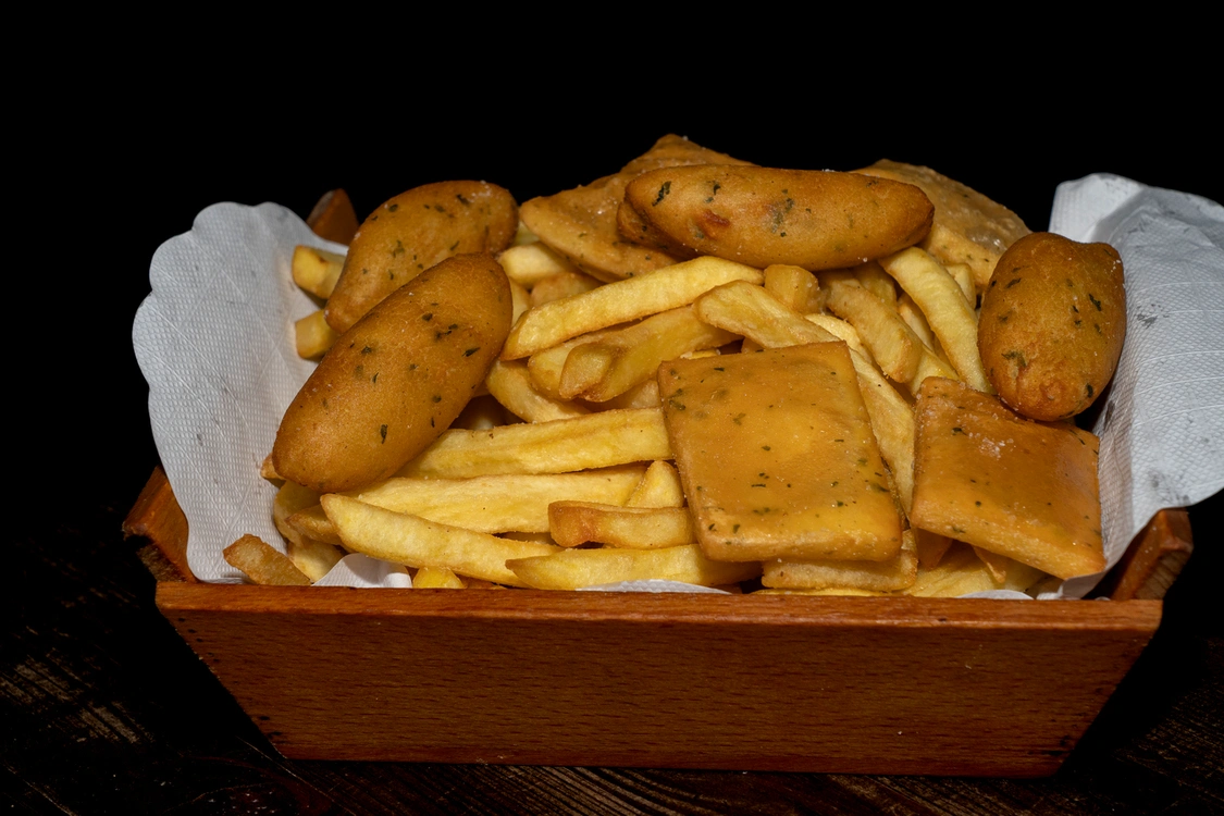 Ricco vassoio di Antipasto Caldo tipico siciliano con patatine fritte dorate, crocchè di patate e panelle di ceci servito su carta assorbente — Pizzeria Alla Botte, Misilmeri.