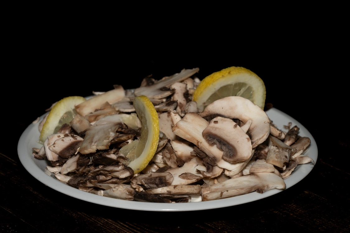ntipasto di funghi champignon freschi affettati sottilmente, conditi con olio, limone, sale, pepe e origano, guarniti con fette di limone fresco — Pizzeria Alla Botte, Misilmeri.