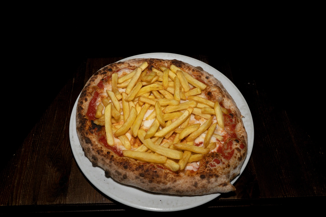 Pizza Pata Pizza con base pomodoro e fior di latte, ricoperta da un'abbondante porzione di patatine fritte dorate — Pizzeria Alla Botte, Misilmeri.