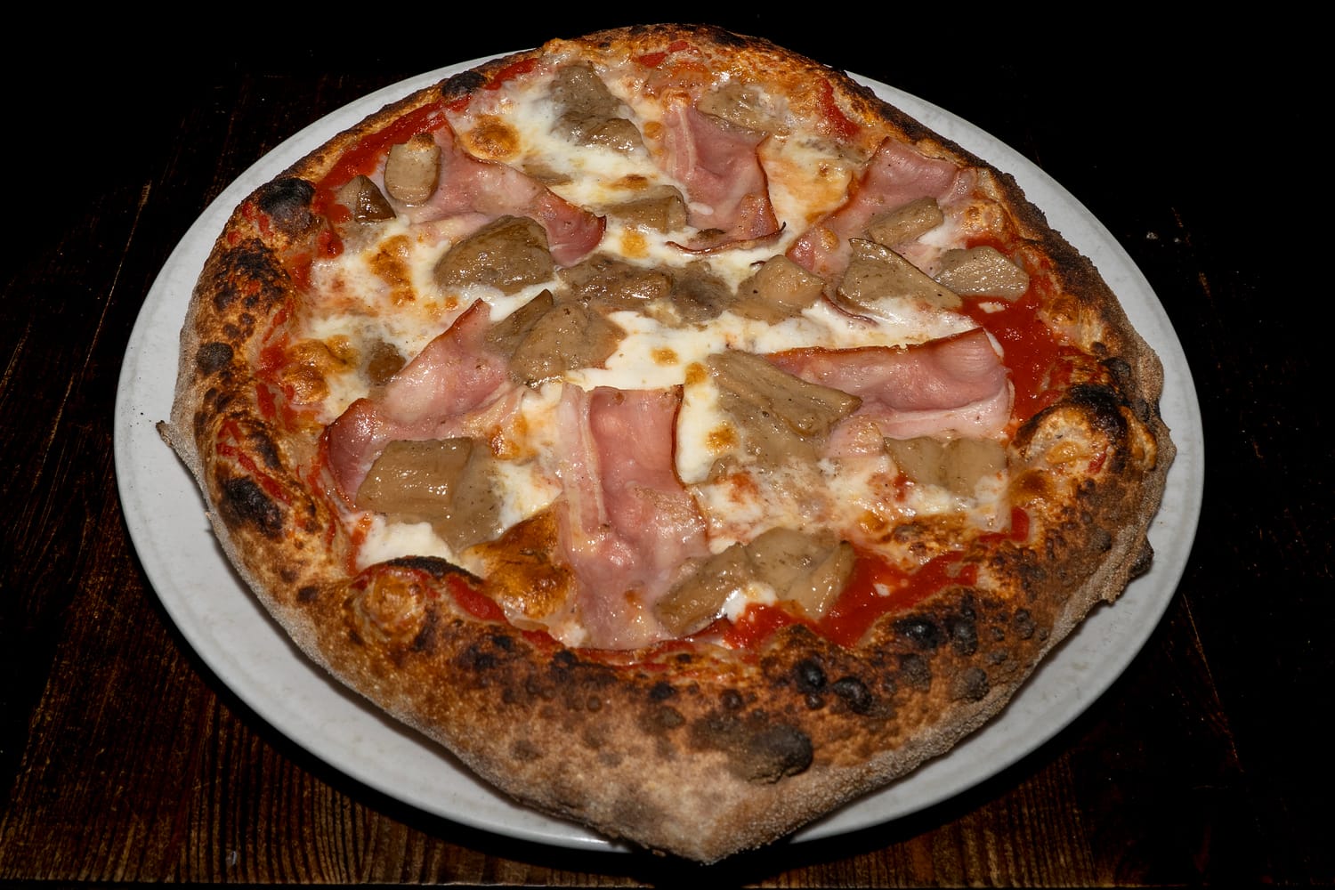 Pizza ai Porcini con base di pomodoro e fior di latte, guarnita con fette di funghi porcini e bacon croccante, cotta in forno a legna — Pizzeria Alla Botte, Misilmeri.