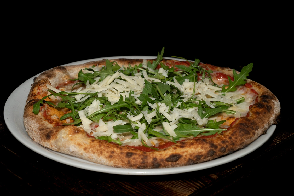Pizza alla Rucola con base di pomodoro e fior di latte, guarnita con un abbondante letto di rucola fresca e scaglie di grana — Pizzeria Alla Botte, Misilmeri.