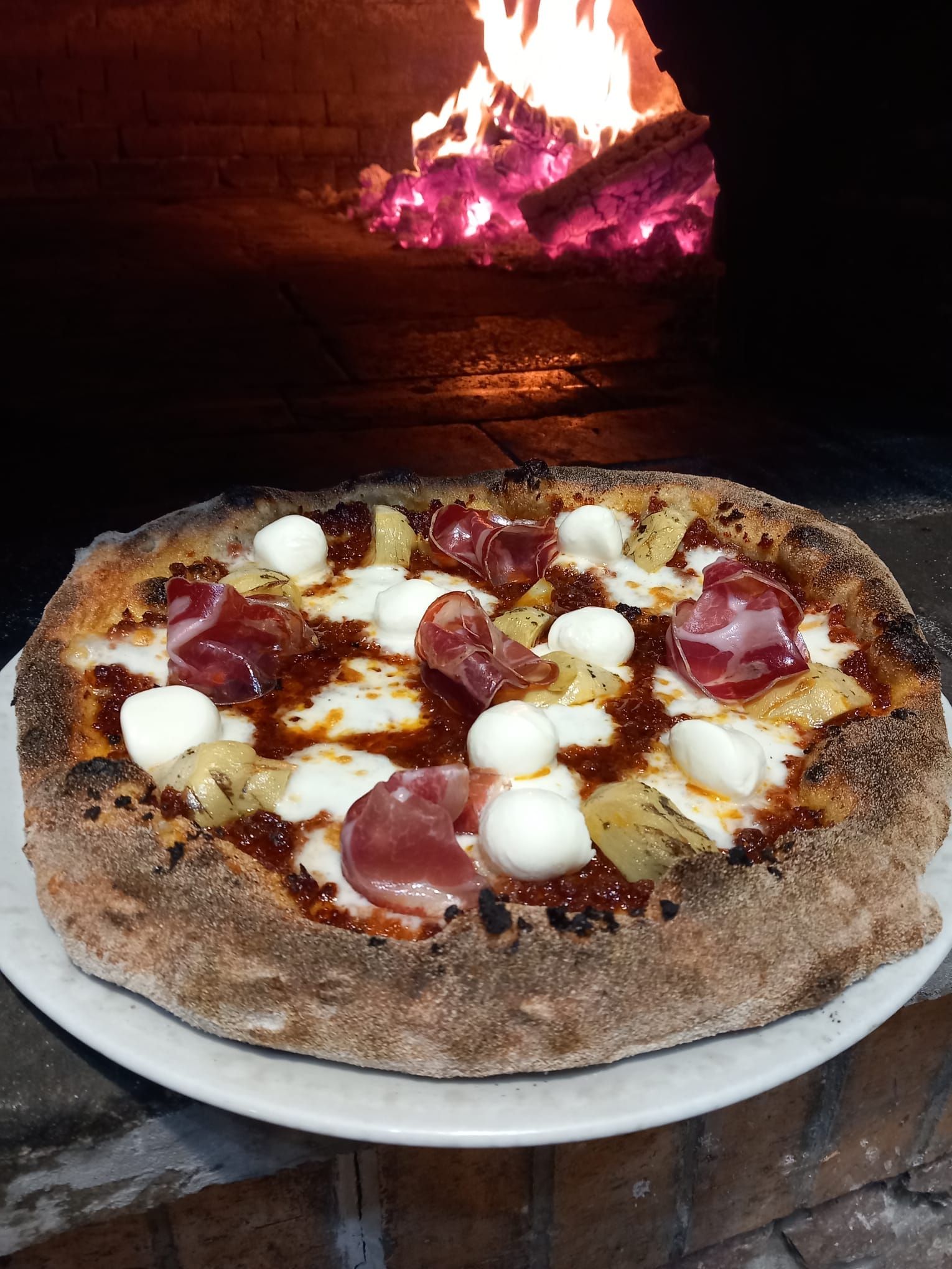 Pizza gourmet Contadina con base di crema di datterino rosso, mozzarella filante, carciofini arrostiti, rosette di coppa di maialino, ciliegine di mozzarella fresca e petali di mandorle — Pizzeria Alla Botte, Misilmeri.