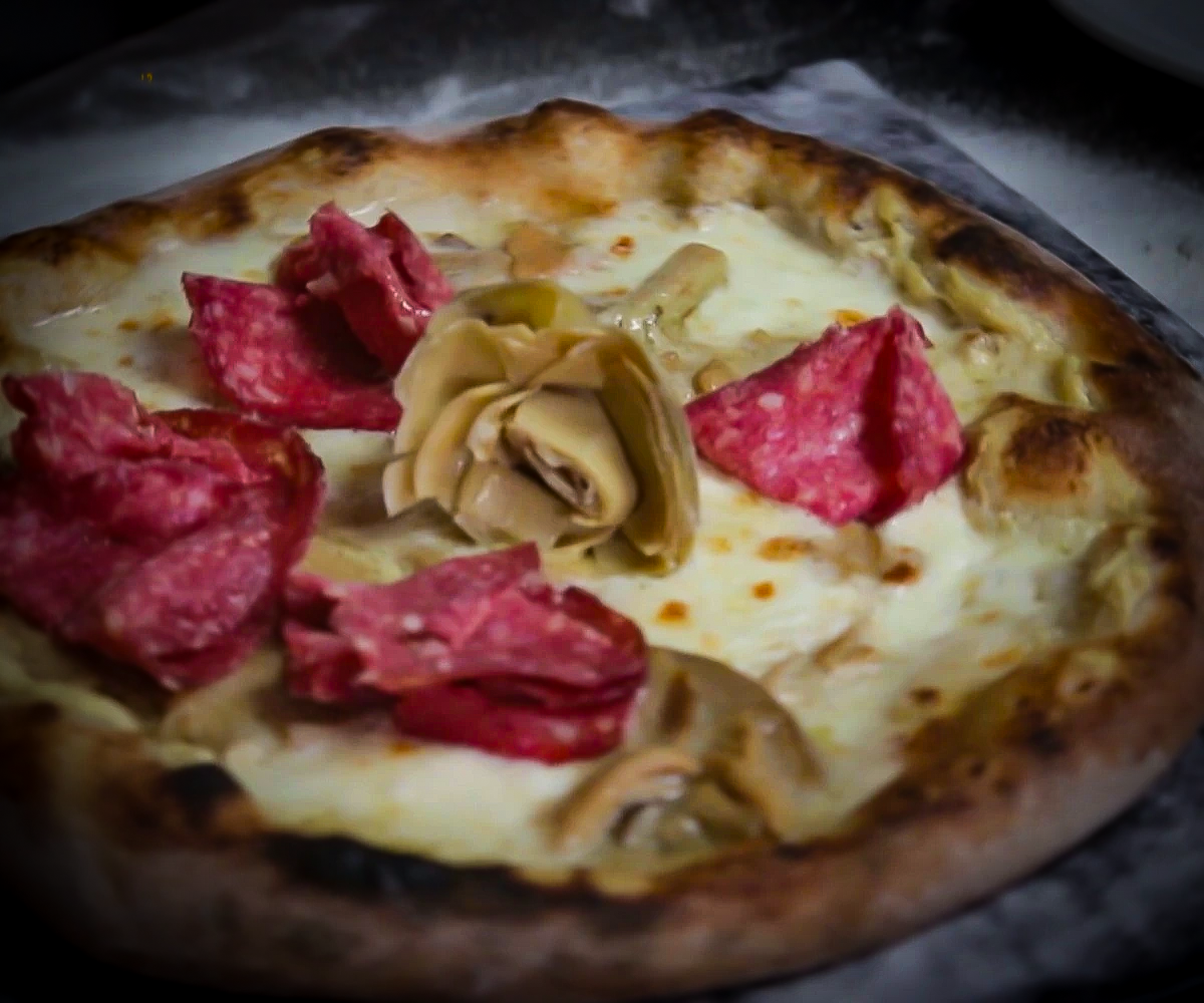 Pizza "La Gustosa" con impasto integrale, crema di carciofi, fior di latte, funghi porcini, cuori di carciofo e salame alle erbe della Pizzeria "Alla Botte" a Misilmeri.