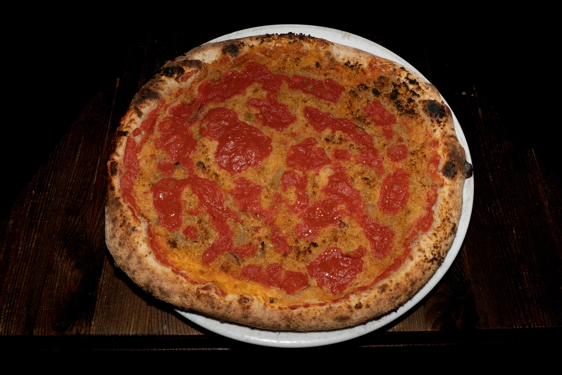 Pizza Origanata tradizionale con base di pomodoro a ciuffi, mollica tostata, cipolla, acciughe e grana grattugiato, cotta in forno a legna — Pizzeria Alla Botte, Misilmeri.