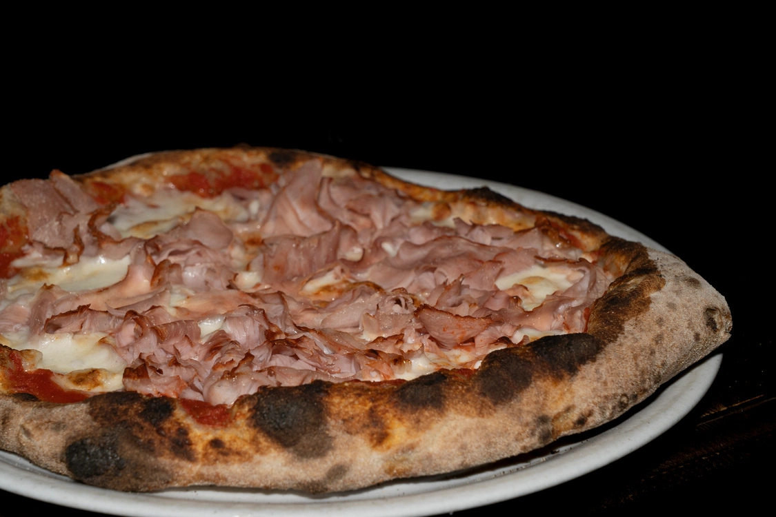 Pizza Romana con base di pomodoro saporito, fior di latte filante e un'abbondante copertura di fette di prosciutto cotto, cotta in forno a legna — Pizzeria Alla Botte, Misilmeri.