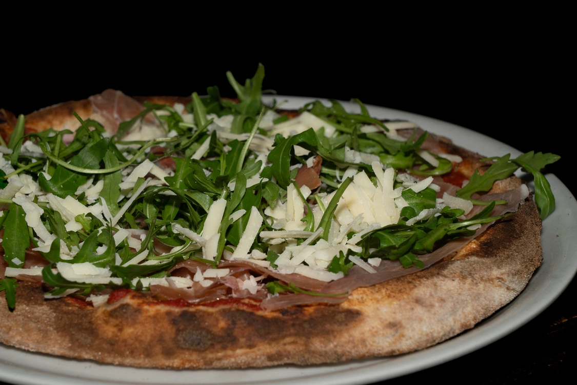 Pizza San Daniele artigianale con base pomodoro e fior di latte, ricoperta da fette di prosciutto crudo, rucola fresca e scaglie di grana — Pizzeria Alla Botte, Misilmeri.