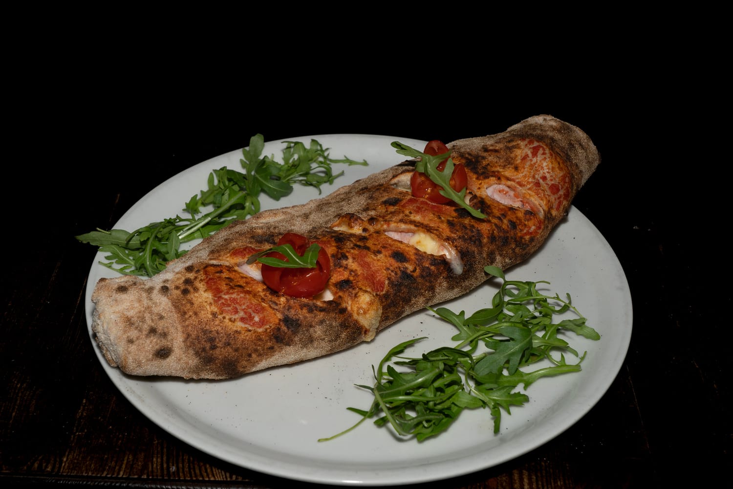 Sfilatino artigianale dalla forma allungata e croccante, farcito con pomodoro, fior di latte, prosciutto cotto ed emmental, guarnito con rucola e pomodorini freschi — Pizzeria Alla Botte, Misilmeri
