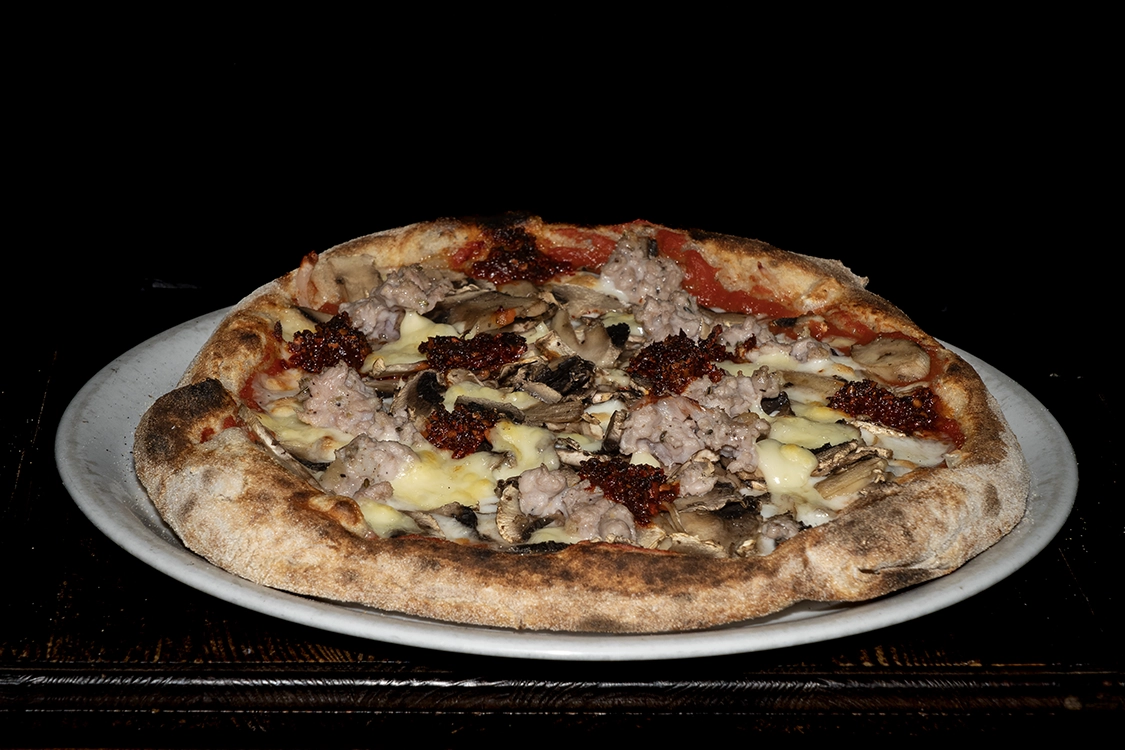 Pizza Talenduja artigianale con base pomodoro, fior di latte e taleggio, farcita con 'nduja piccante, salsiccia e funghi freschi, cotta nel forno a legna — Pizzeria Alla Botte, Misilmeri.
